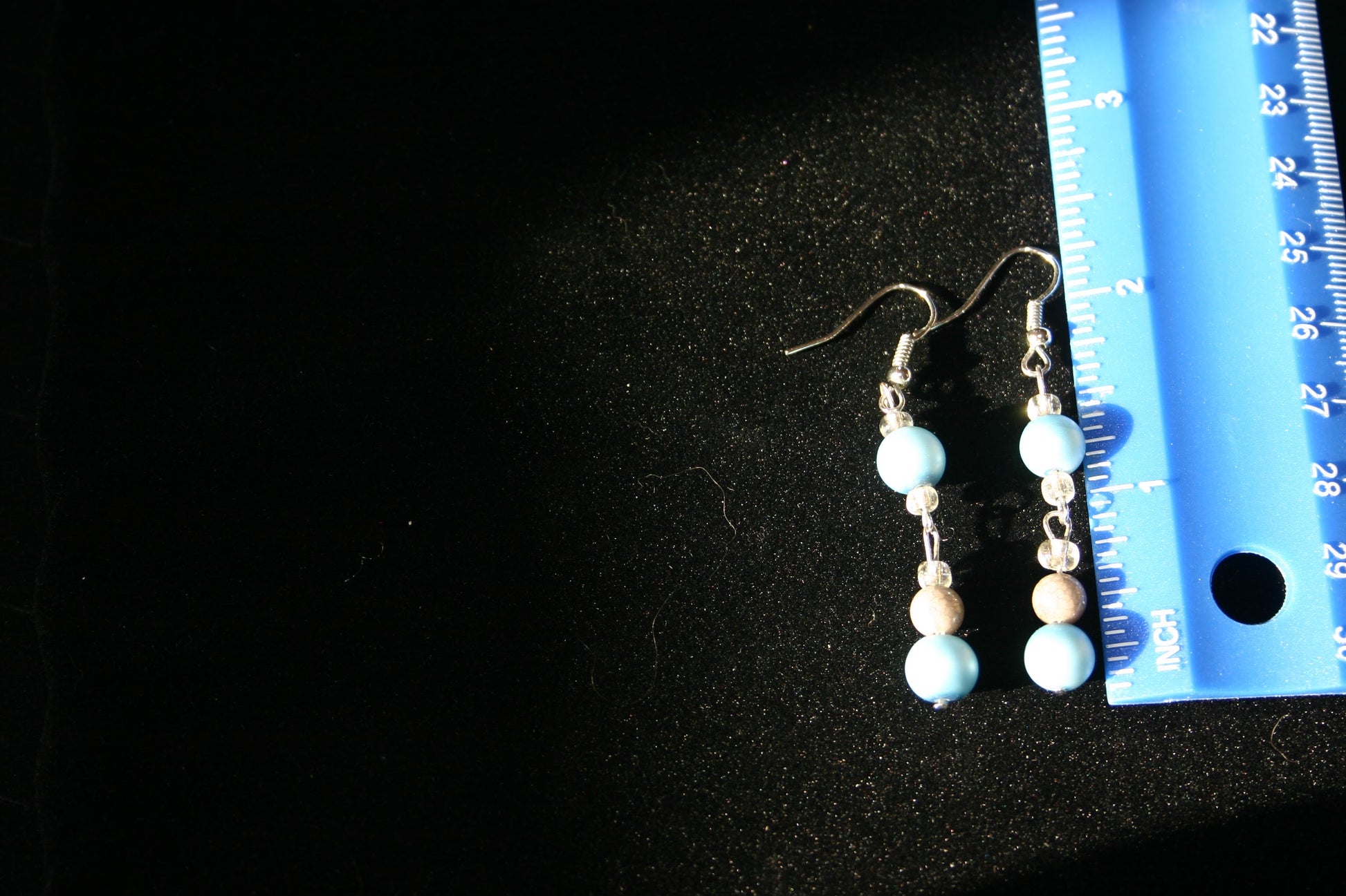 Earrings next to a ruler showing they are 2 inches long 