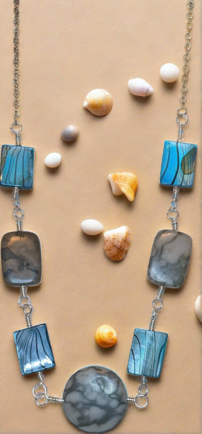 Close up of linked component necklace.  The wire wrapped links are of grey marble canyon and dyed shell alternating.  The center is a round marble canyon bead and the other beads are rectangular. 