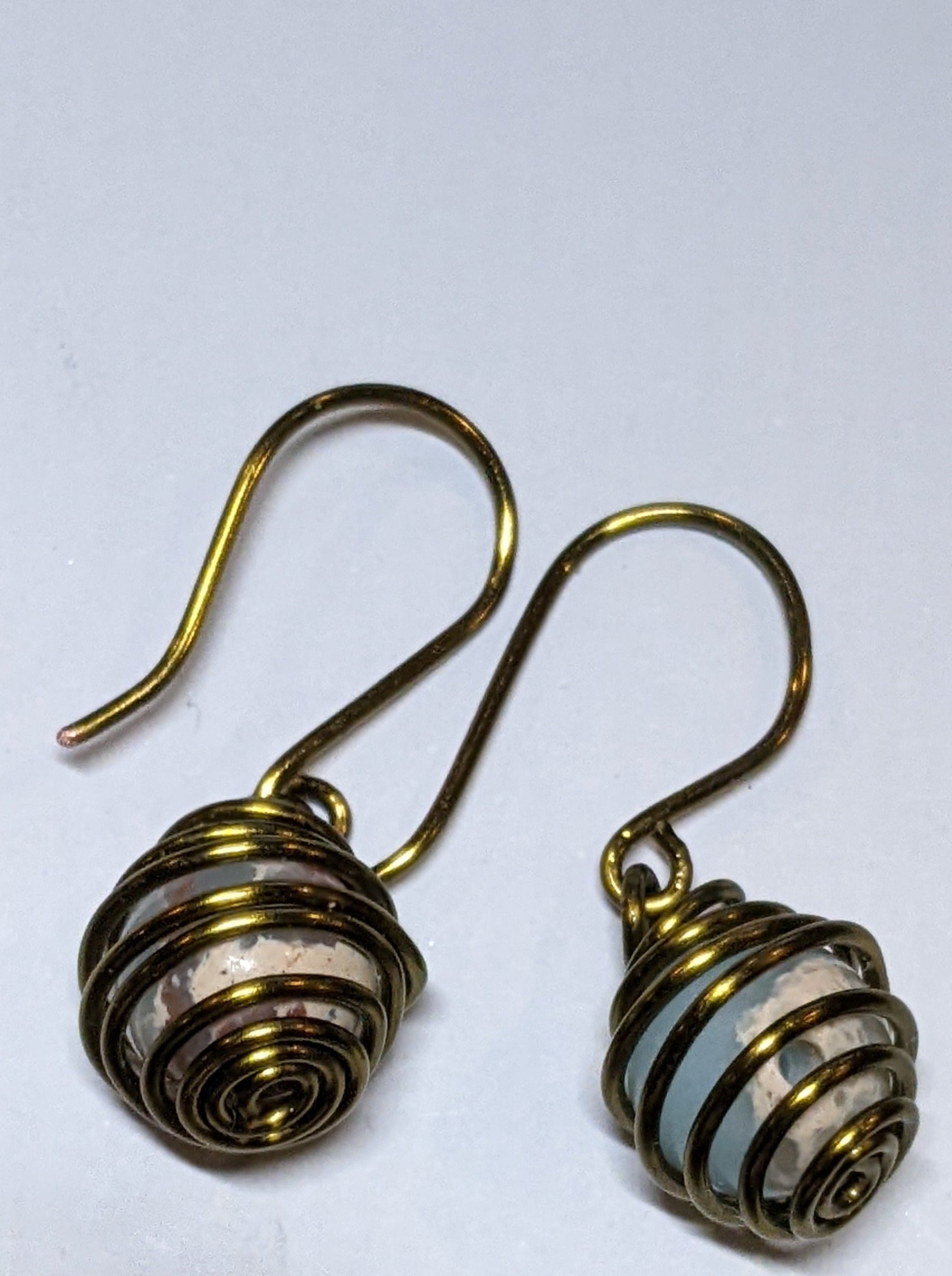 Close up of caged bead earrings made of bronze wire and jasper beads