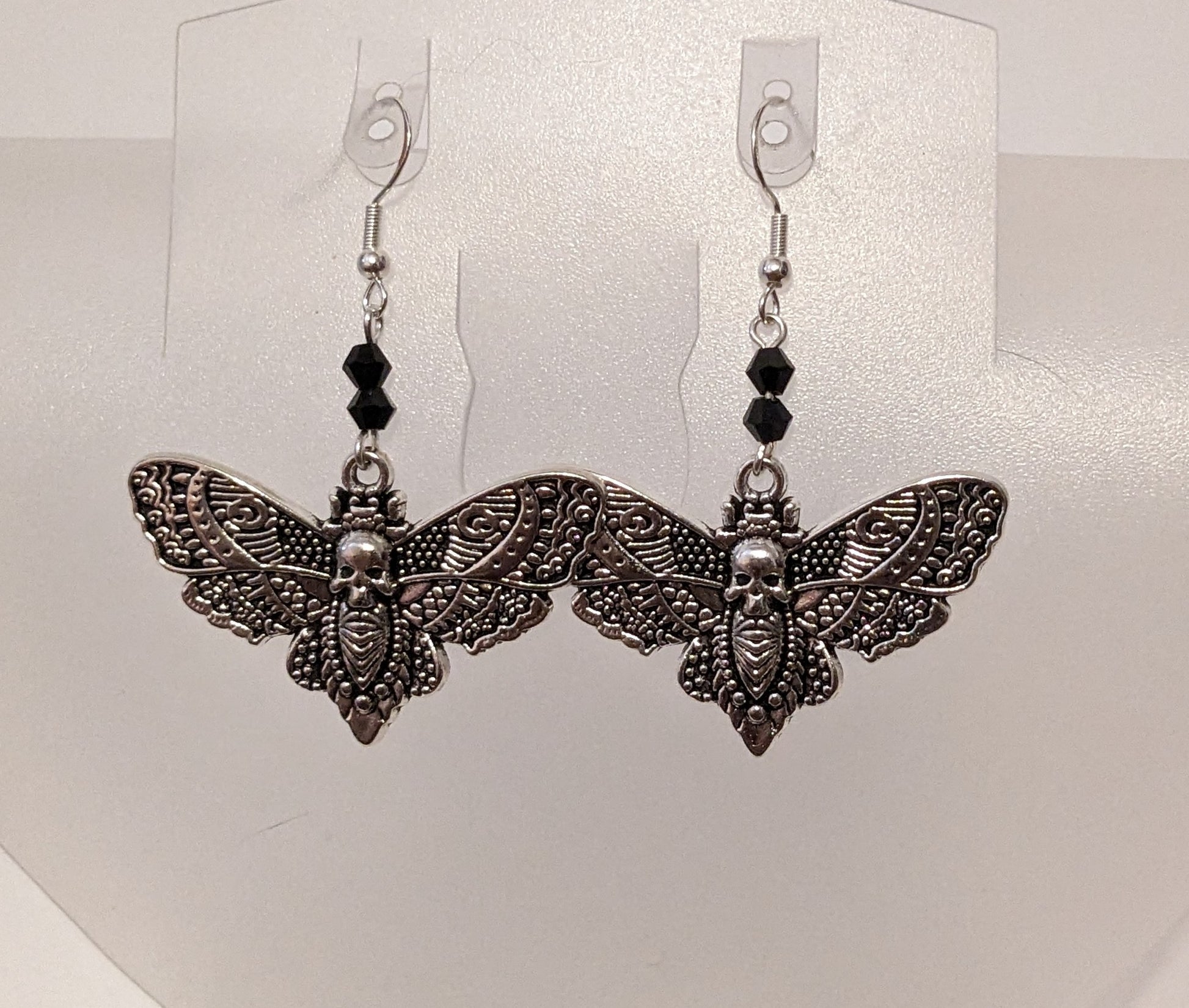 Close up of earrings showing the intricate details on the deaths-head moth charms. 