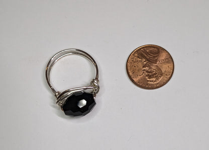 Wire wrapped black faceted glass ring next to a US penny for scale