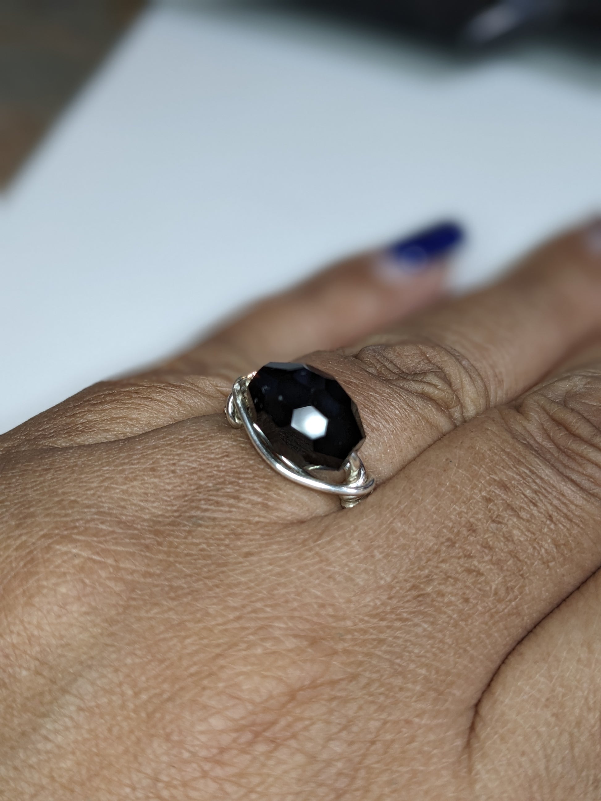 Wire wrapped black faceted glass ring on a brown person's hand