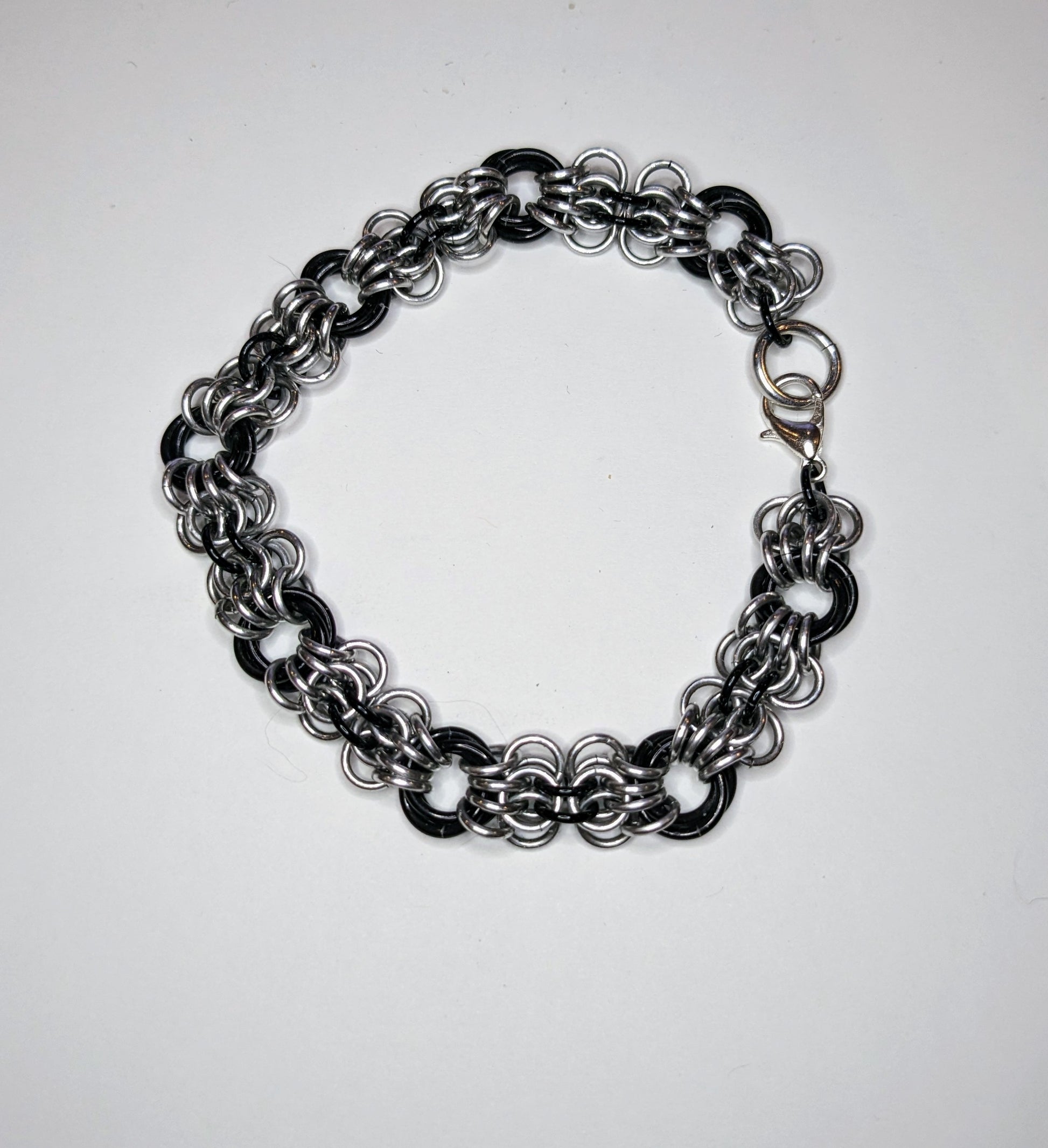 Silver and black butterfly weave chainmail bracelet on a white background.  Bracelet has a lobster clasp.