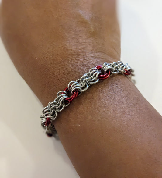Silver and red butterfly weave chainmail bracelet on a brown wrist