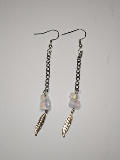 Dangle earrings that are a long chain with translucent glass beads with aurora borealis finish and a silver feather charm at the bottom 