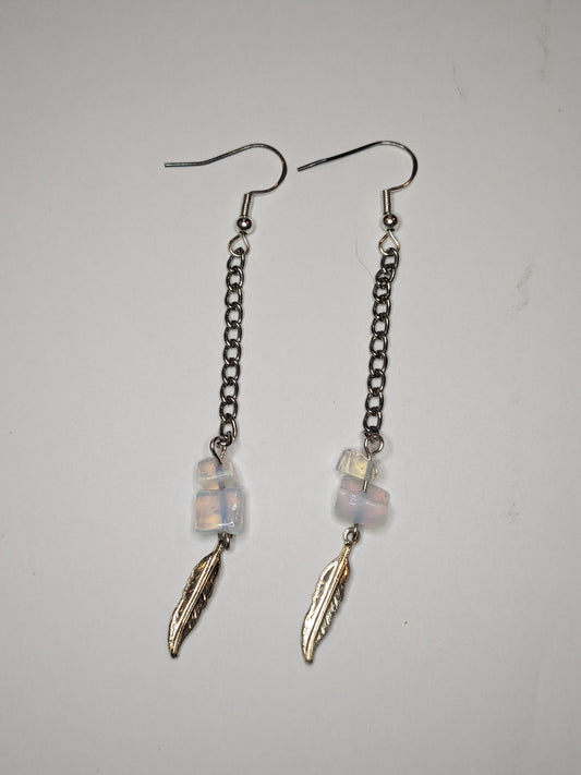 Dangle earrings that are a long chain with translucent glass beads with aurora borealis finish and a silver feather charm at the bottom 