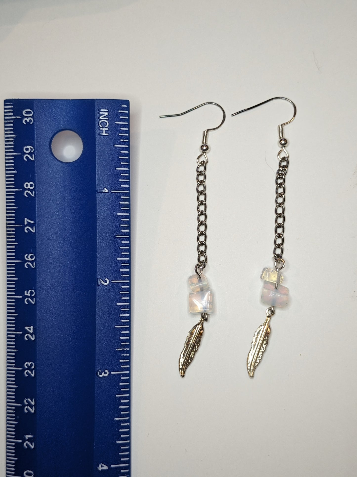 Earrings next to a blue ruler showing the earrings are 3 inches long. 