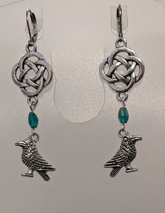 Earrings with silver toned raven charms, a blue - green crystal beads and a silver Celtic knot. 