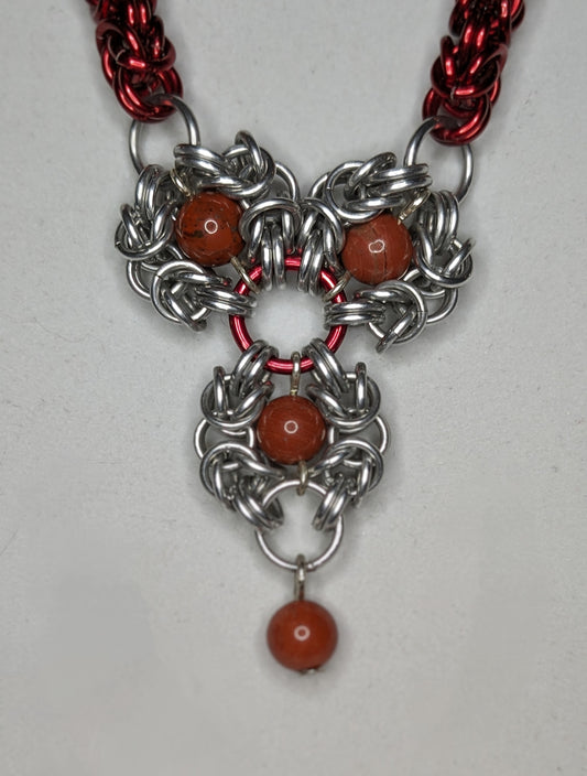 Close up of the focal: three Romanov flowers with red jasper bead centers linked in an upside down triangle. A red jasper bead dangling from the bottom. 