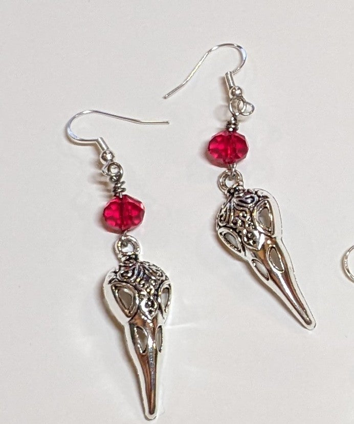 Silver creepy cute bird skull charms topped with faceted red crystal bicone bead